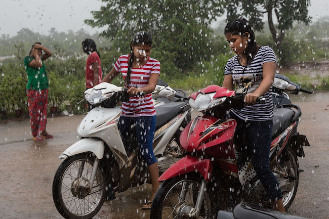 Burmese women start their bikes during a heavy rainstorm outside a market in the planned Dawei SEZ (Photo by Taylor Weidman/Getty Images)